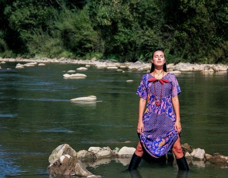 A Brunette Girl Stands Knee-deep In A Mountainous Green River In
