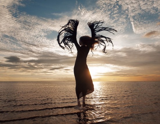 Elegant woman dancing on water. Sunset and silhouette
